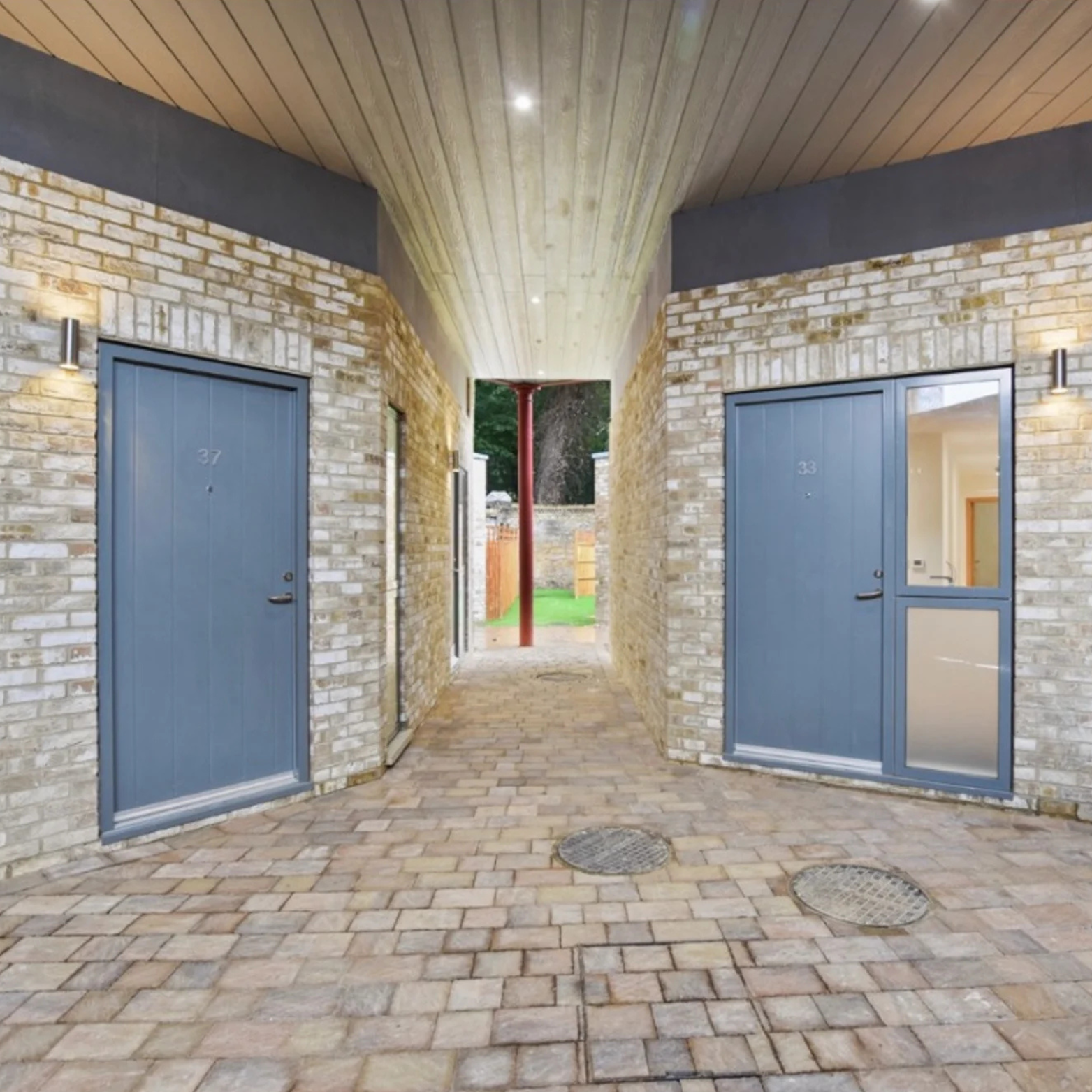 Contemporary exterior with two grey bespoke doors, brick walls, and timber ceiling crafted by DT Carpentry Kent.