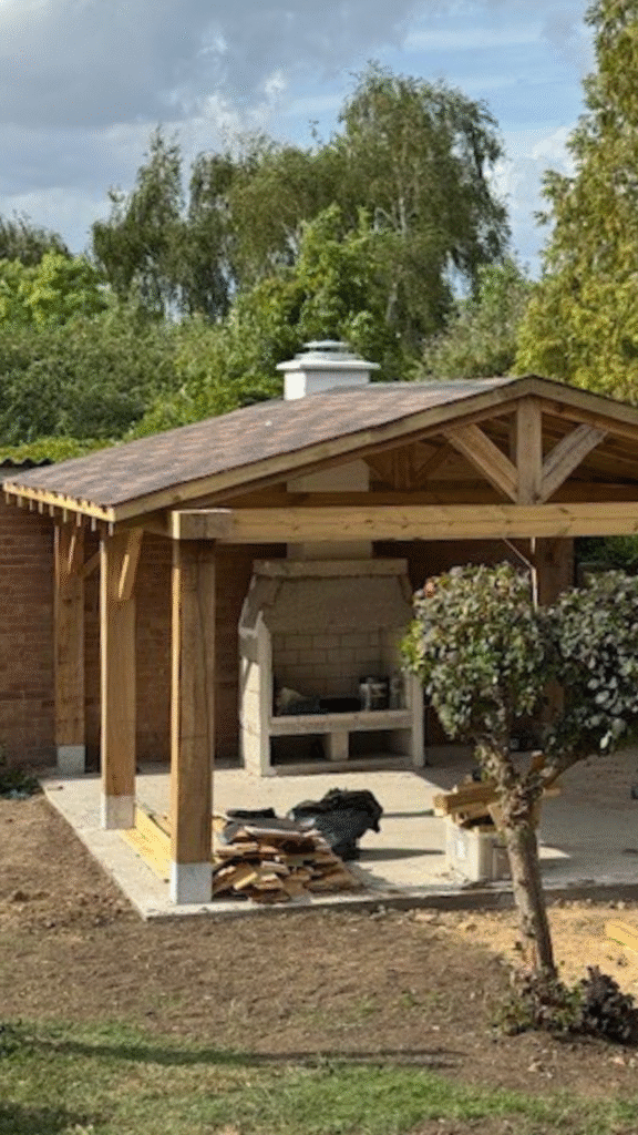 Timber garden pavilion with pitched roof and outdoor fireplace