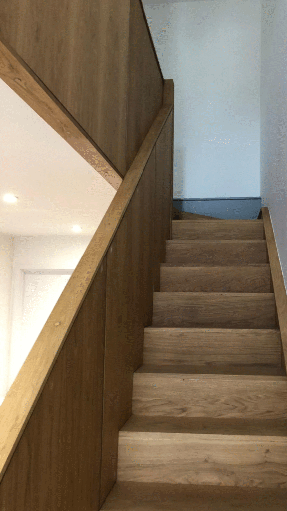 Wooden staircase with matching oak banister and wall cladding