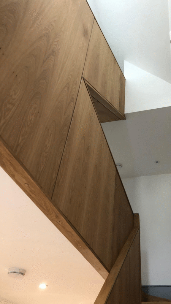 Bespoke oak staircase with full-height wall panelling in modern home